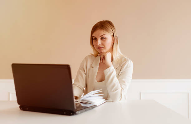 istock Young woman using laptop and documents sitting at the table in her living room. Working from home 1281515465