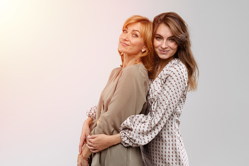 Happy beautiful women: mother and adult daughter closeup portrait isolated on white background