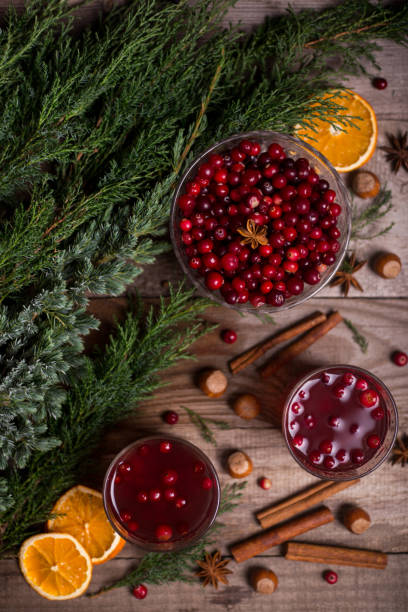 Two glasses of cranberry drink, cranberries, cinnamon sticks, anise stars on a wooden background Two glasses of cranberry drink, cranberries, cinnamon sticks, anise stars on a wooden background. Christmas winter drinks. winter still life stock pictures, royalty-free photos & images