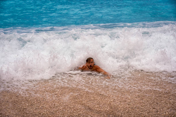 Young guy playing in big waves at Myrtos beach