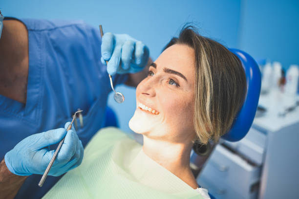 istock Dentist examining a patient's teeth using dental equipment in dentistry office. Stomatology and health concept. Young handsome male doctor in disposable medical facial mask, smiling happy woman. 1281521711