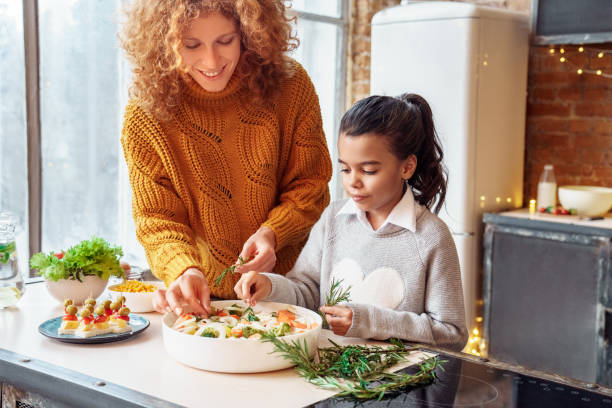 glückliche lockige frau und mulatten mädchen nichte macht gesunde vegane nahrung für familie schlemmen - humor mother 20s adult stock-fotos und bilder