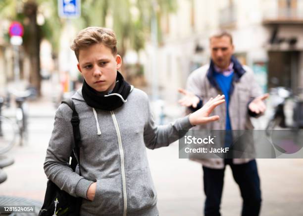 Frowning Teenager Gesturing Enough While Man Reprimanding Him Stock Photo - Download Image Now