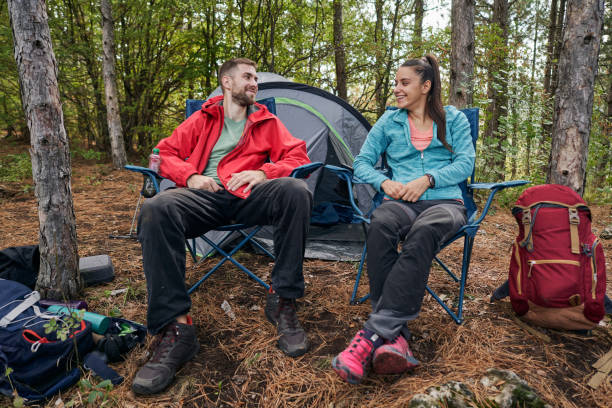 schönes junges paar in der liebe camping zusammen in einem bergwald - campingstuhl stock-fotos und bilder