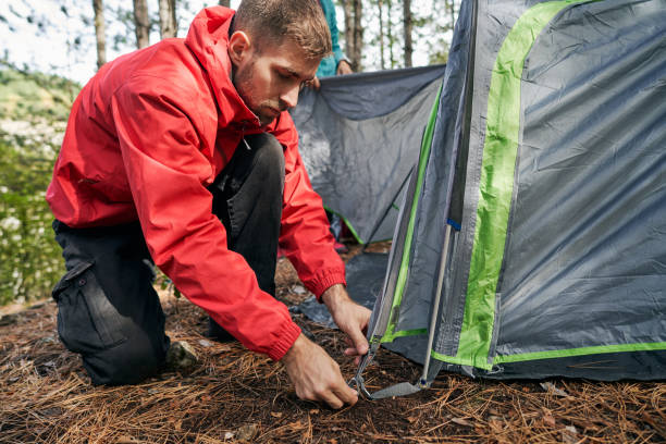 istock Young hiker camper in a jacket setting up a tent in the mountains 1281527067