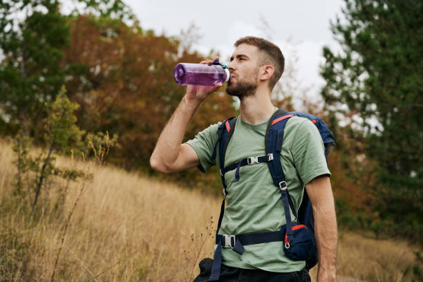 istock Thirsty male hiker drinking water while climbing the mountain 1281527150