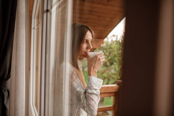 Young female standing after taking a shower in the morning on balcony of the hotel. holding a cup of coffee or tea in her hands. Looking outside nature forest and Mountain Young female standing after taking a shower in the morning on balcony of the hotel. holding a cup of coffee or tea in her hands. Looking outside nature forest and Mountain. prison meal stock pictures, royalty-free photos & images