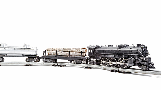 Vintage model train engine with a log car and oil tanker.