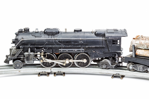 Vintage model train engine with a log car.