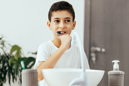 10 year old boy brushing his teeth in the bathroom