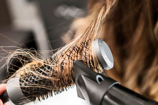 Mujer joven en una peluquería, peluquero usando secador de pelo photo