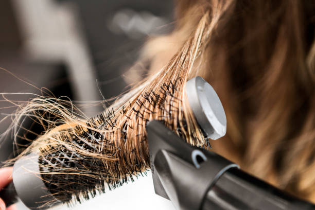 young woman at a hair salon ,hairdresser using hairdryer - hair care hairbrush hair dryer human hair imagens e fotografias de stock