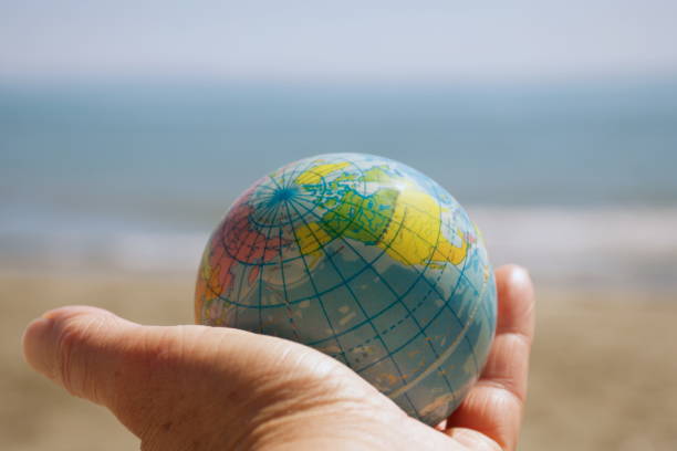 istock Personal Perspective, Hand Holds a Globe Ball by Sea 1281533015