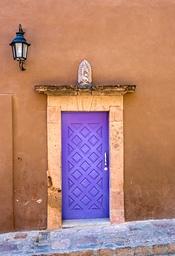 A bright purple door in a stone frame and a brown wall