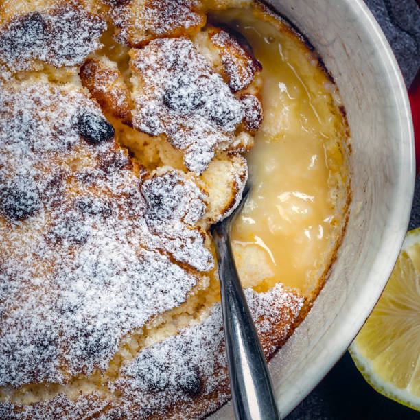 istock Lemon pudding, top view in baking dish with serving spoon.  Delicious self-saucing dessert. 1281539988
