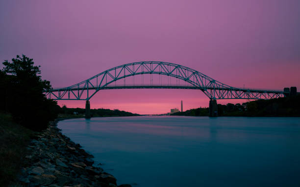istock Sagamore Bridge and Cape Cod Canal Twilight Nightscape Silhouette Photo, Pink, and Turquoise Colored Cross-processed Panoramic Image. 1281541998