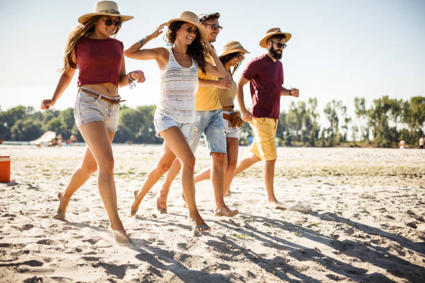 istock Group of friends running on the beach for fun 1281542853