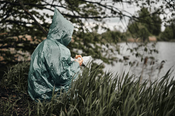 ein mann mit bart im grünen regenmantel isst in der natur. bewölktes wetter, fast food. - 11311 stock-fotos und bilder