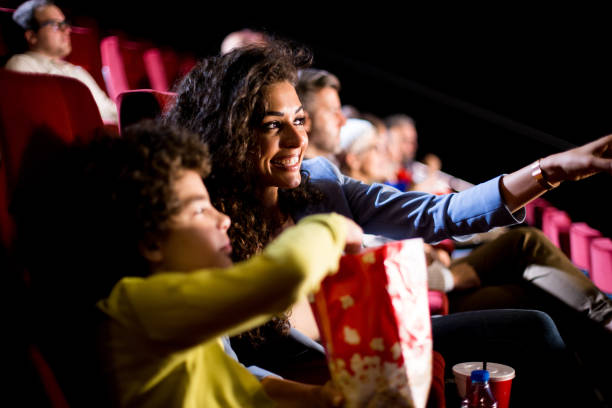 Happy woman enjoying with her son at the cinema Boy watching movies at the cinema with mother. film industry stock pictures, royalty-free photos & images