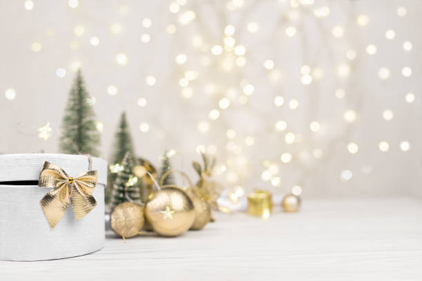 sfondo natalizio, scatola regalo bianca con fiocco d'oro sullo sfondo del bokeh natalizio. copia spazio - snow bound foto e immagini stock