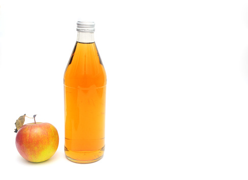 One whole apple with leaf and a bottle of apple cider vinegar on white background, copyspace
