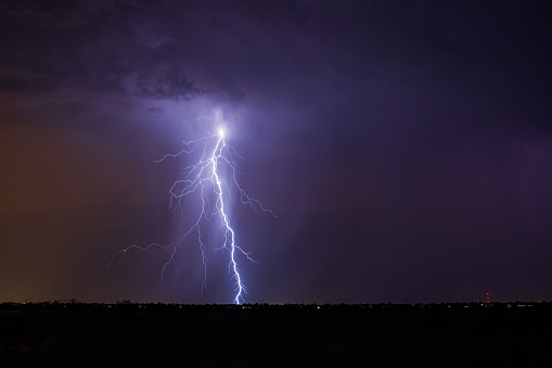 Lightning bolt strike in a storm over a city at night.