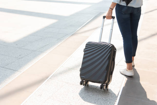 空港で女性とスーツケースのトロリー荷物を閉じます。人とライフスタイルの概念。旅行とビジネス旅行のテーマ。女性は一人でソロの女の子によってツアーや世界中を旅に行くジーンズを� - female mobility blank teenage girls ストックフォトと画像