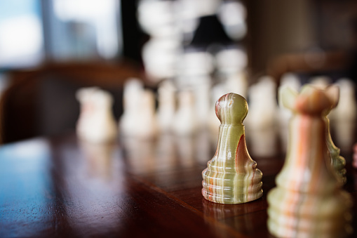 Old marble chess piece on an antique wooden chess table.