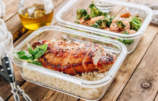 Keto lunchboxes - grilled chicken with cauliflower rice and chicken and broccoli Keto lunchboxes - grilled chicken with cauliflower rice and chicken and broccoli in soy sauce with sesame seeds on a rustic wooden table. Top view lunch box stock pictures, royalty-free photos & images