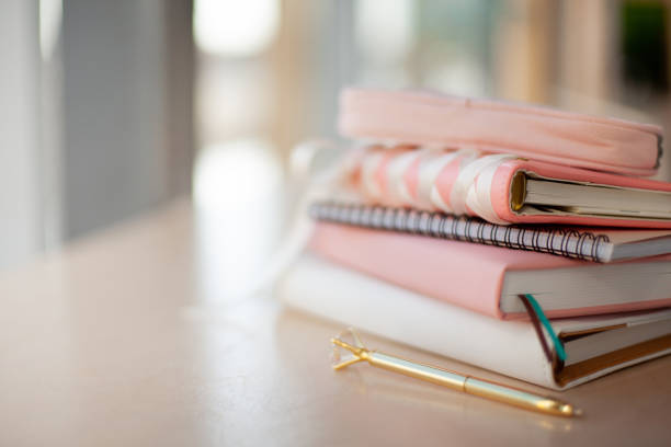 istock stylish designed coral and white coloured stack of diaries with gold pen 1281560176