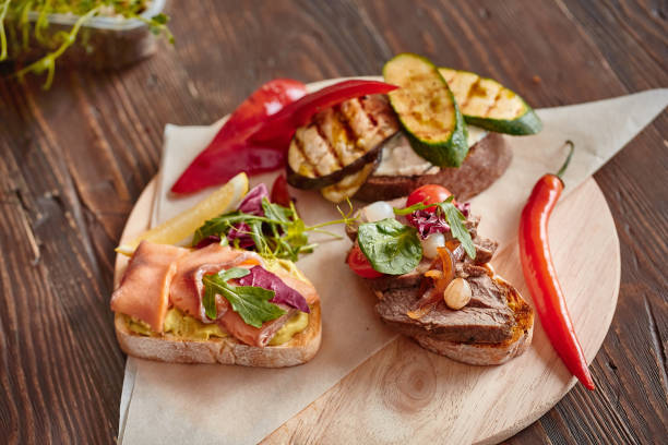 istock Assorted different bruschetta on a wooden round Board on a brown background. Bruschetta with various products-cheese, fish, meat, vegetables and fresh herbs. Italian antipasti 1281565178