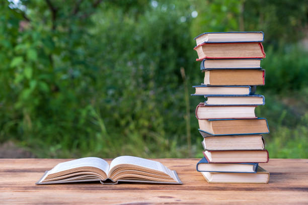 istock Stack of books on wooden table over nature background, outdoors 1281573113
