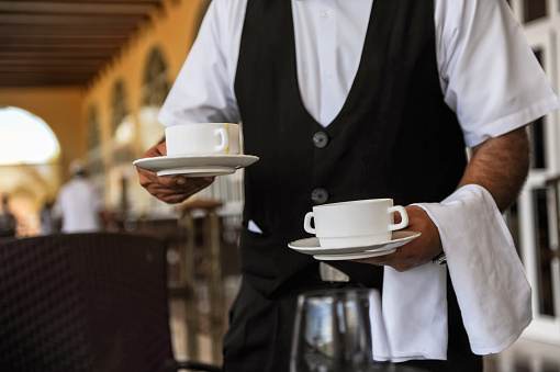 Midsection of waiter carrying bowls of soup