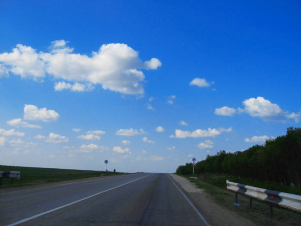 istock Wide highway and meadow. Clouds over and blue sky 1281575085