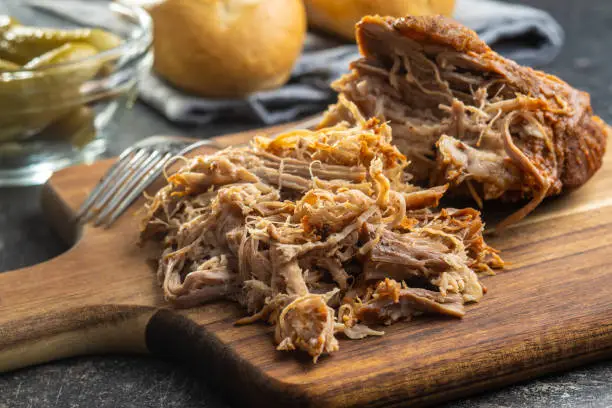 Pulled pork meat on cutting board.