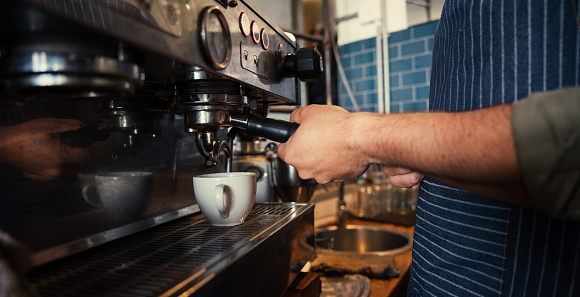 Male barista brewing coffee for customers in funky restaurant