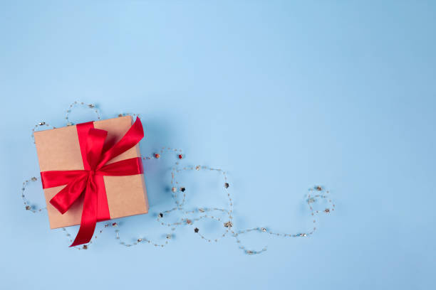 istock Present box with red tape bow and Christmas decorations on festive blue background with copyspace for your text. Flat lay style. Christmas, New Year, Valentines Day or birthday celebration concept 1281578431