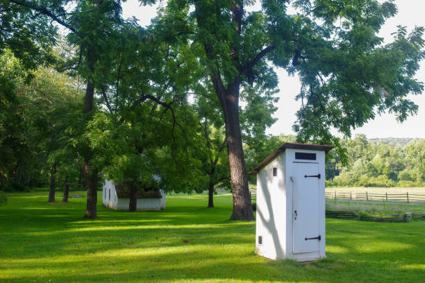 istock Colonial outhouse by a white stone cottage in idyllic setting. 1281580799