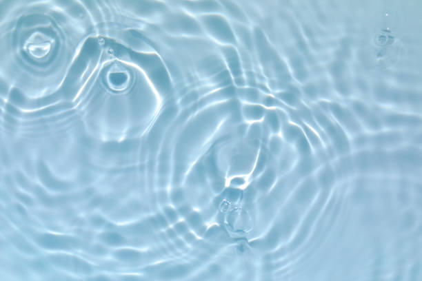 transparent blue colored clear calm water surface texture De-focused blurred transparent blue colored clear calm water surface texture with splashes and bubbles. Trendy abstract nature background. Water waves in sunlight with copy space. makeup product photography stock pictures, royalty-free photos & images