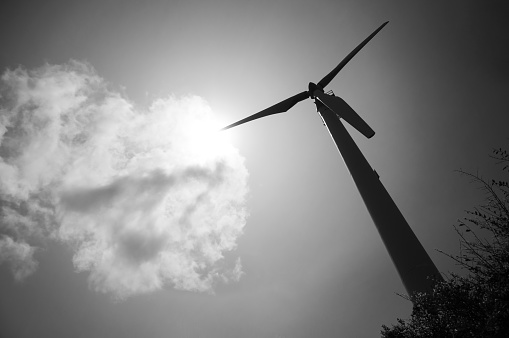 Large wind turbine against bright sky silhouette in black and white. Wind power plant clean energy technology