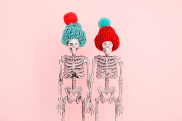 selective focus pair of  skeletons wearing cute knitted hat on a pink background