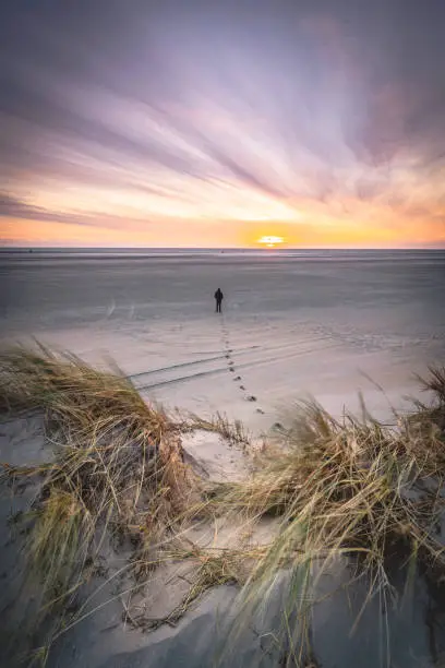 An ethereal shot of a single man walking on the endless beach of Lakolk Strand in Western Denmark. It is one of the widest beaches in Europe and the biggest in Scandinavia.