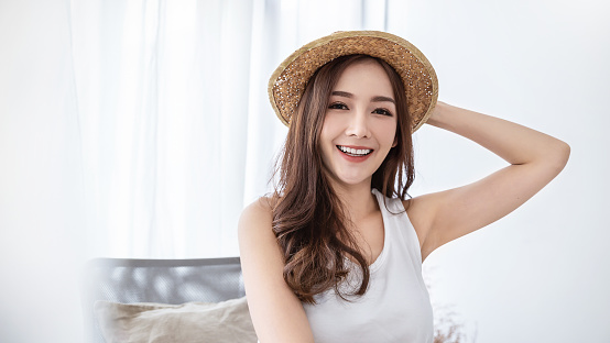 Portrait of young beautiful asian woman on holiday vacation summer time in white bedroom. Happy cheerful girl in summer. Korean makeup skincare. University woman fashion lifestyle concept.