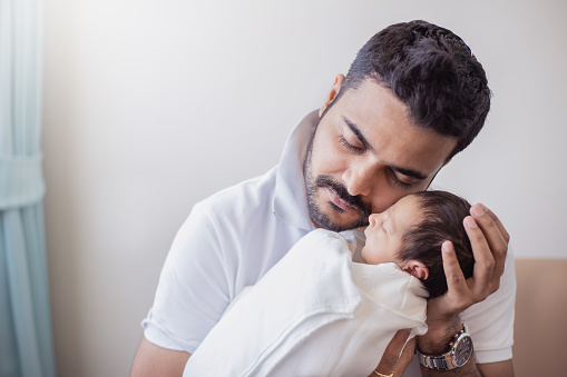 Closeup portrait of young asian Indian father holding his newborn baby with copy space. Healthcare and medical daycare nursery love lifestyle together single dad fatherâs day holiday concept