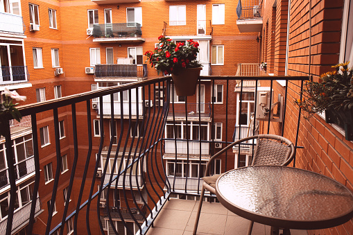 Cozy balcony with flowers. View of the courtyard of a brick house.