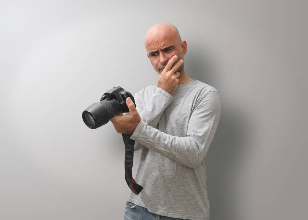 Attractive dark-haired bald man with three-day beard, gesturing and  glad to take good photos