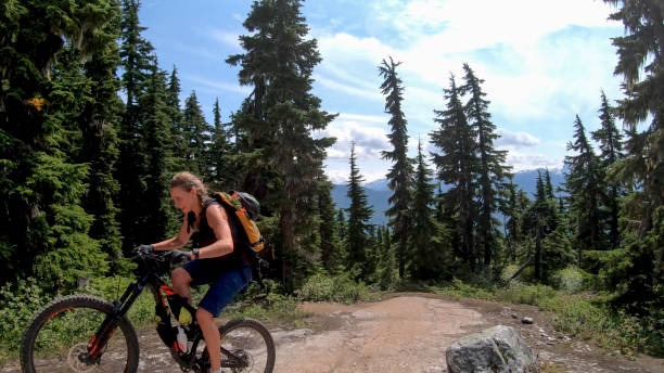 istock Female mountain biker rides up alpine trail 1281594745