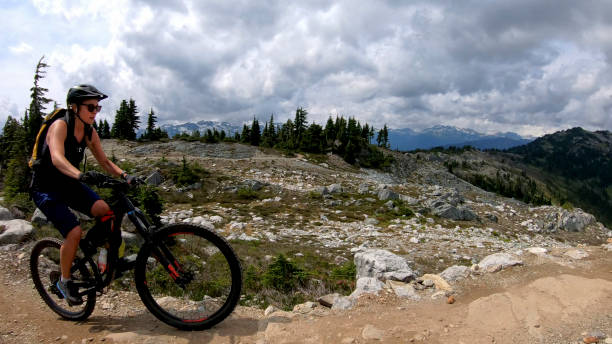 istock Female mountain biker rides up alpine trail 1281595332