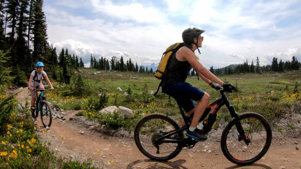 istock Female mountain bikers ride along alpine trail 1281595353