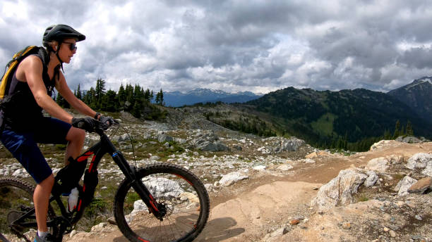 istock Female mountain biker rides up alpine trail 1281595364